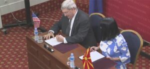 A man and woman sitting at a desk signing papers.