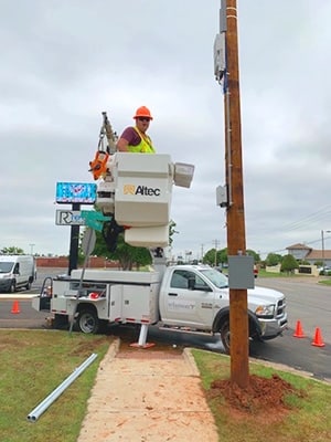 A worker is working on a pole in front of a truck.