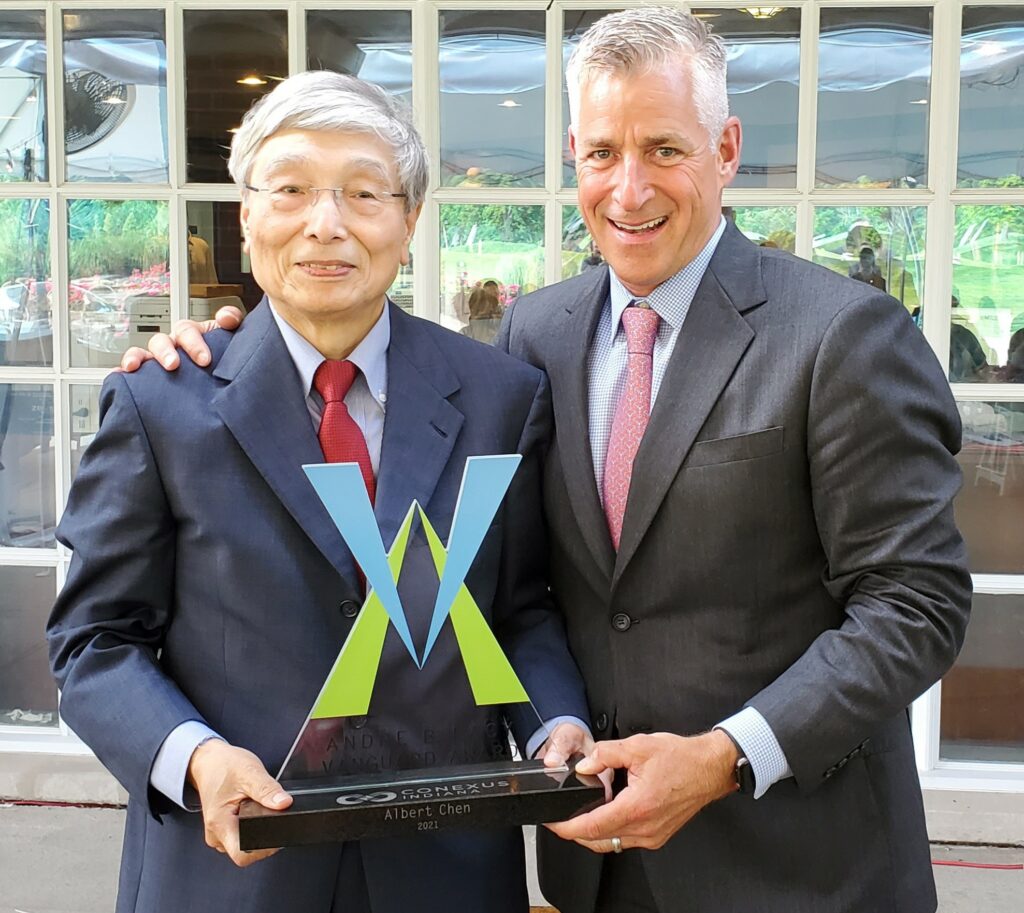 Two men in suits standing next to each other holding an award.