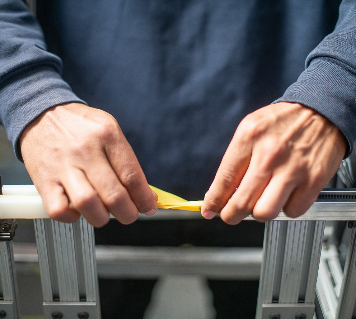 Person gripping a piece of yellow tape with both hands, focusing on the task.