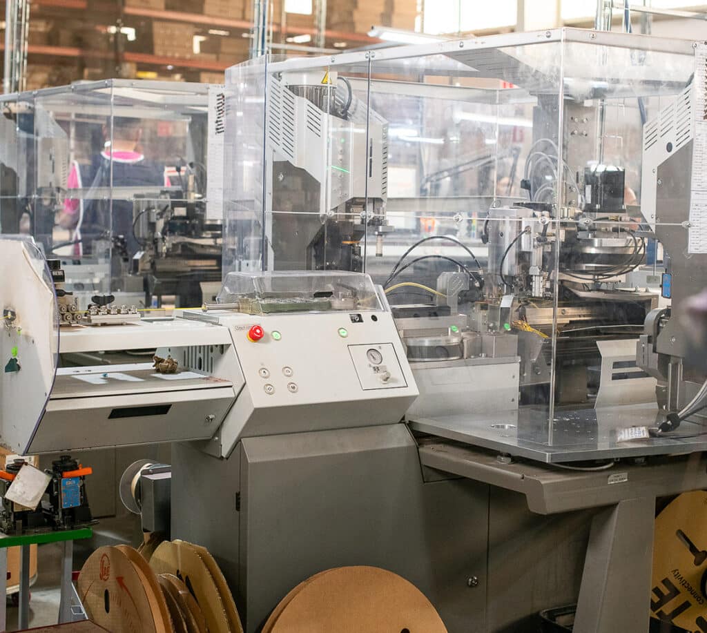 Industrial-grade laser cutting machine in operation within a manufacturing facility, surrounded by various machinery components and materials.