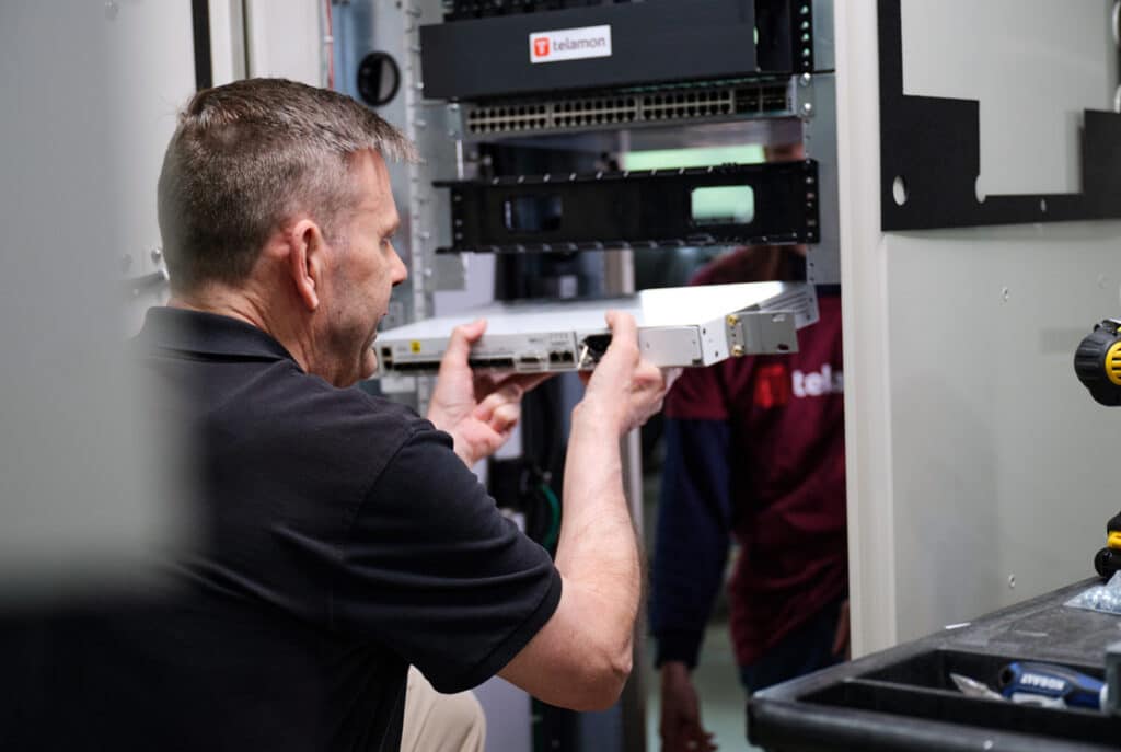 A man installs or removes a piece of equipment in a server rack in a data center.