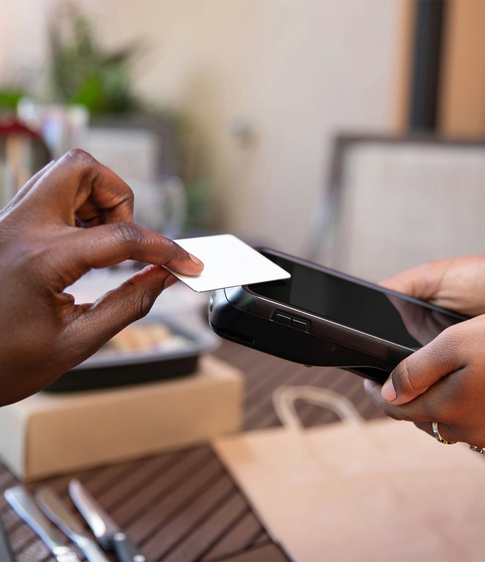 A person makes a contactless payment using a white card on a point-of-sale device.